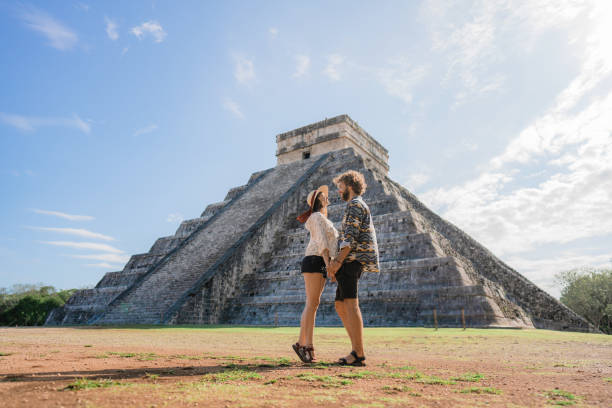 paar im hintergrund der chichen itza pyramide in mexiko - travel to mexico stock-fotos und bilder