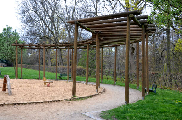 round pergola, trellises made of wooden poles around the sandpit with play elements for children. around is a path and lawns. benches for moms to rest. stakes in japanese chinese style - school bench above bildbanksfoton och bilder