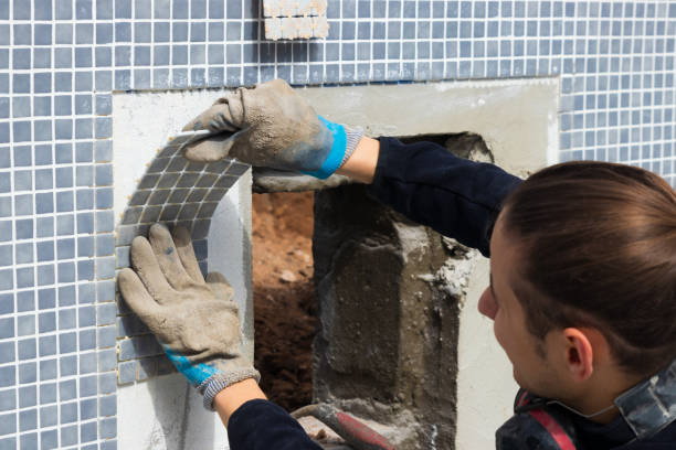 Tiling blue and grey pool by a technitian in a modern swimming pool under construction