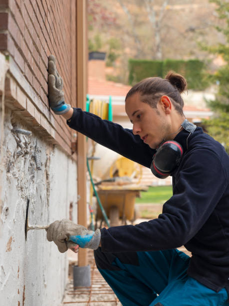 istock Construction man working appliying cement and concrete plaster on house wall 1393595506