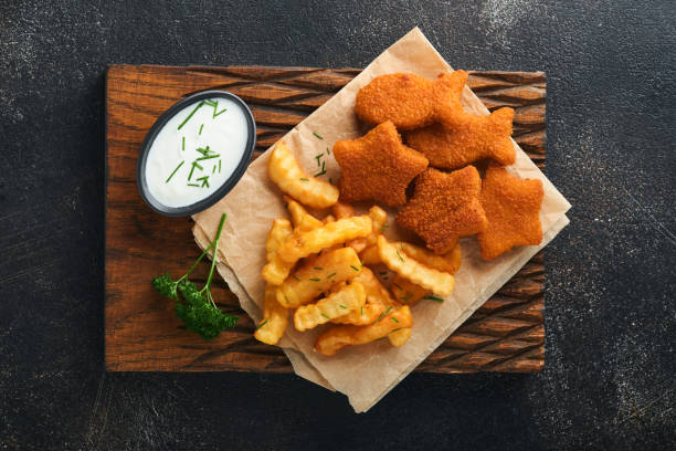 Fish and Chips british fast food. Fish Sticks with french fries set on rustic board on dark old concrete background. Traditional British authentic street food or takeaway food. Mock up. Top view. fish and chips comida rápida británica. palitos de pescado con papas fritas colocadas sobre tabla rústica sobre fondo oscuro de hormigón viejo. comida callejera tradicional británica auténtica o comida para llevar. maqueta. vista superior.