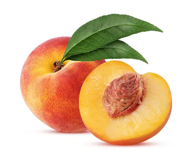 Photo of Peach fruit one cut in half with green leaf