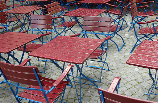 many wet chairs and tables of the alfresco cafe after rain without people