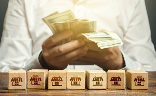 Blocks symbolizing business network and businessman counting money. High income from commercial real estate rent. Taxes payment. Building a successful business empire. Franchise concept. Investments bloques que simbolizan la red empresarial y el hombre de negocios que cuenta el dinero. altos ingresos por alquiler de bienes raíces comerciales. pago de impuestos. construyendo un imperio empresarial exitoso. concepto de franquicia. inversiones