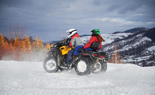 Portrait of man and woman riding on offroad four-wheeler ATV. Concept of active leisure and winter activities.
