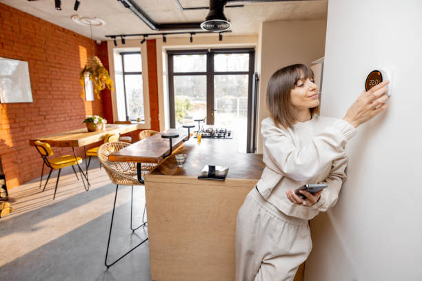 Woman controlling home temperature with electronic thermostat