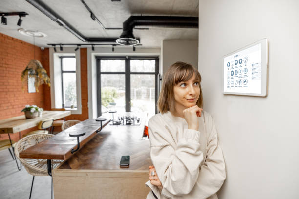 istock Woman controlling home devices with digital smart panel mounted on the wall 1393601891