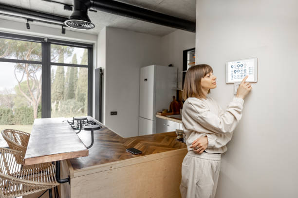 istock Woman controlling home devices with digital smart panel mounted on the wall 1393601898