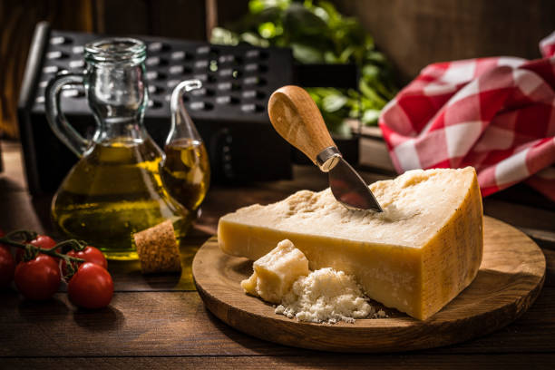 parmigiano reggiano su un tavolo rustico in legno - parmigiano foto e immagini stock