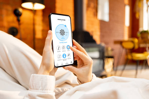 istock Woman holding phone with running smart home application 1393601975