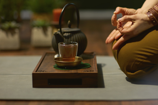 Cup with red fruit tea, teapot and sugar bottle on round wooden tray on wooden window sill, cafe. Front view.