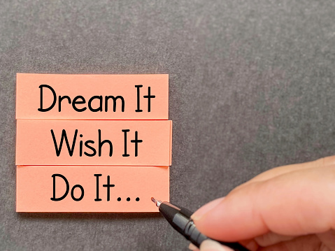Motivational and inspirational quote - dream it wish it do it text written on notepaper background. Stock photo.