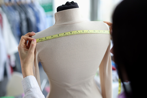 Close-up of female fashion designer takes measurements with centimeter. Tailor woman sewing fashion clothes. Designer, art and sewing concept