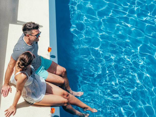 giovane coppia innamorata seduta a bordo piscina - travel the americas human age viewpoint foto e immagini stock