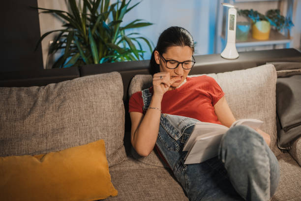 woman reading at home - nail biting imagens e fotografias de stock