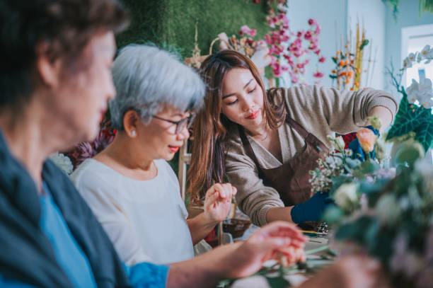 азиатские китайские пожилые женщины изучают цветочную композицию от женщины-флориста в цветочном магазине - flower arrangement фотографии стоковые фото и изображения