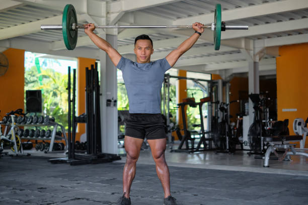 Close-up shot of Indonesian man lifting barbel at gym