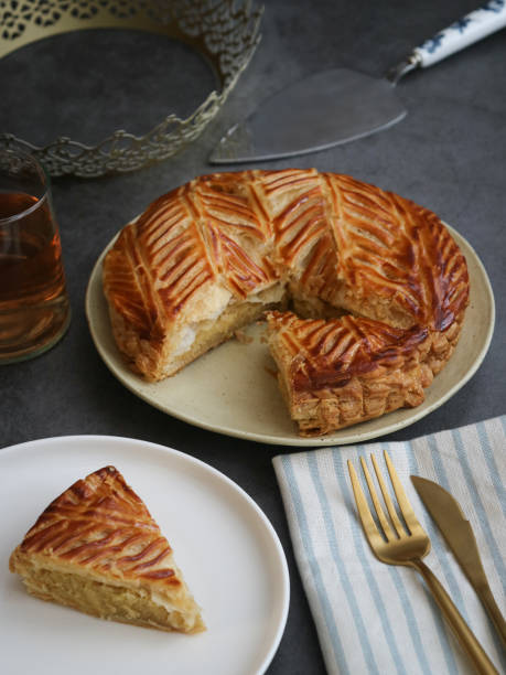 A pieces of traditional French galette des rois or king cake on a white with crown A pieces of traditional French galette des rois or king cake on a white with crown. A traditional cake usually served on Epiphany, made with puff pastry and creamy almond filling galette stock pictures, royalty-free photos & images