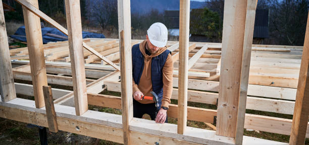 istock Man worker hammering while building wooden frame house. 1393613888