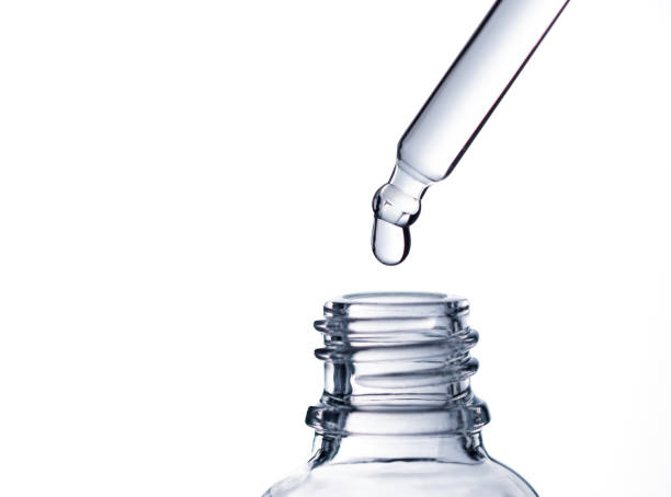 istock Drop of water falling from glass lab pipette in transparent bottle on white background. Macro 1393614021