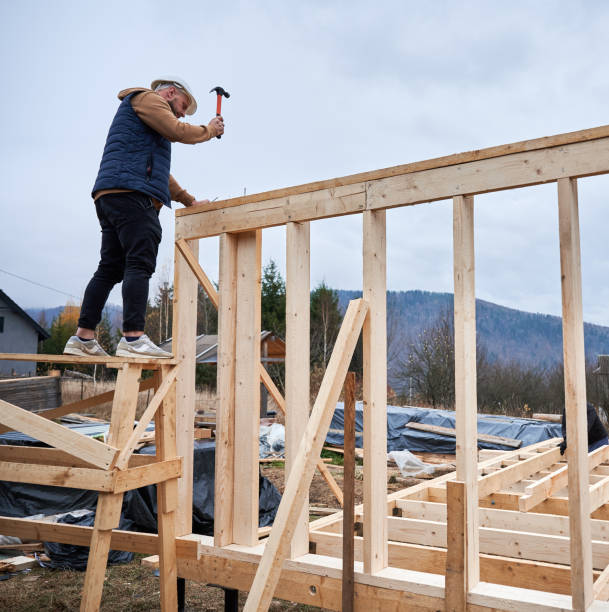 istock Man worker hammering while building wooden frame house. 1393614056