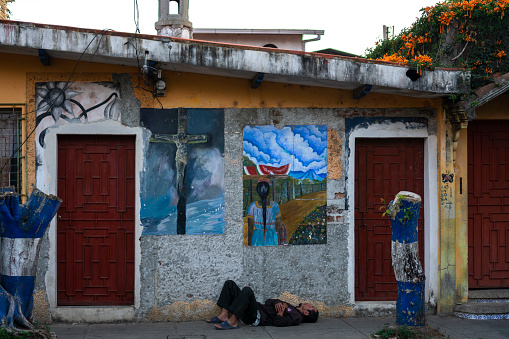 Ruta de las Flores, El Salvador - January 29, 2022: Homeless man sleeping at the door of building with murals in El Salvador
