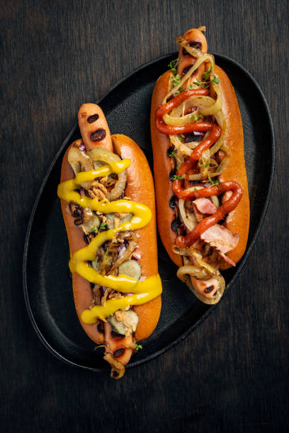 Hot Dogs in Brioche Rolls with Pickles, Onion and Relishes. stock photo