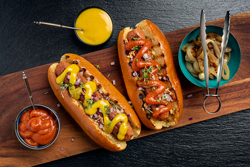 Overhead view of two veggie hot-dogs in brioche rolls with pickles and relishes. Colour, horizontal format with  some copy space.