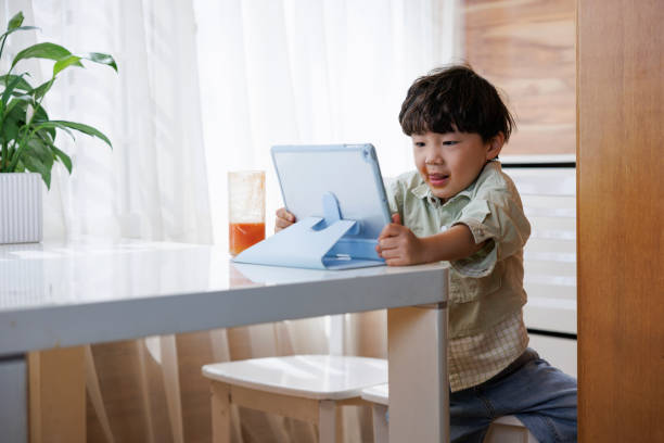 азиатский маленький мальчик играет в игры на цифровом планшете - asian ethnicity child little boys education стоковые фото и изображения