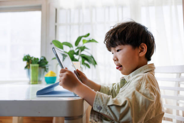 istock Asian little boy playing games on digital tablet 1393616388