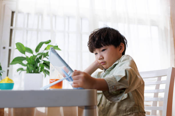 istock Asian little boy playing games on digital tablet 1393616412