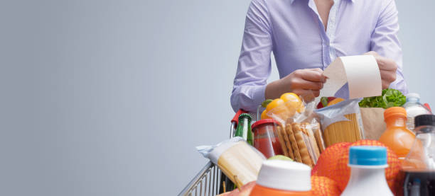 istock Woman checking a grocery receipt and pushing a trolley 1393616459