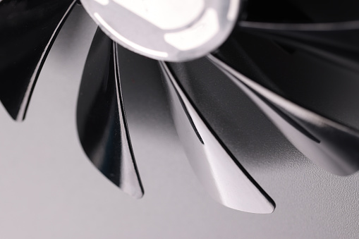 Close-up of cooling fan with black plastic blades on grey background. Car details parts. Device for cooling or ventilation