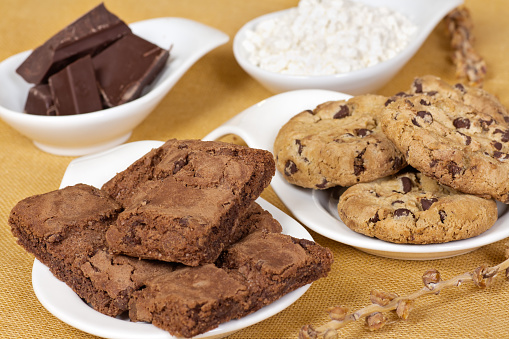 Plates with biscuits, brownies, chocolate, coconut flakes. Sweets ready to eat. Horizontal photo.