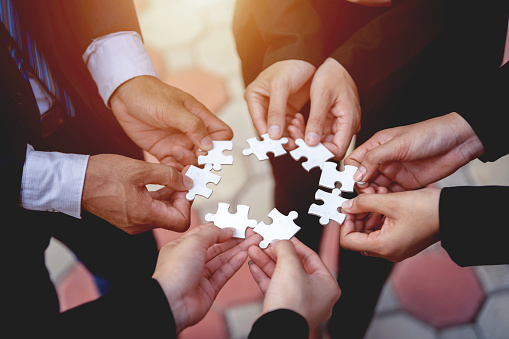 The hand of a businessman holding a paper jigsaw And solving the puzzle together. The business team assembles a jigsaw puzzle. A business group wishing to bring together the puzzle pieces