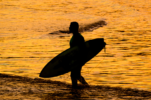 Surfer walking towards the sea of Joaquina Beach. Florianópolis, State of Santa Catarina, Brazil. April 12, 2022.