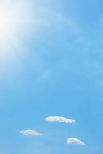 istock Bright blue summer sky with sun shining over soft fluffy clouds 1393621439