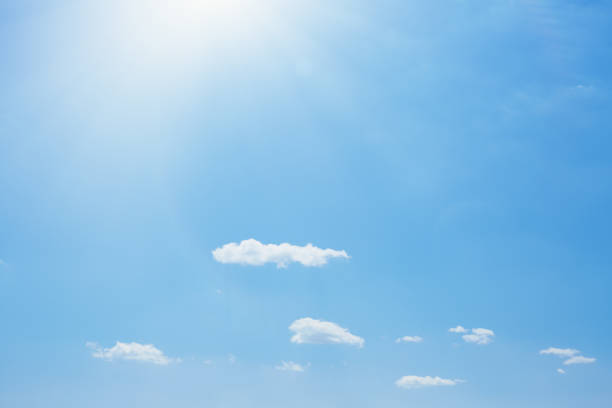 istock Bright blue summer sky with sun shining over soft fluffy clouds 1393621443