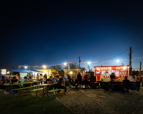 El Paso, Texas, USA - April 22, 2022: An evening crowd gathers for local cuisine under the lights of a truck court.