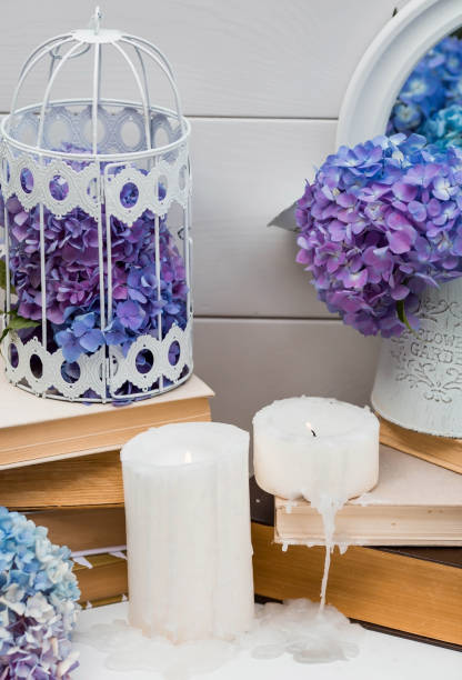 istock A visual element for the content. Still life in vintage style. Old books, candles, a cage with blue hydrangeas on a white wooden table. A holiday card for the wedding day. 1393624341