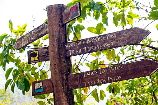 Arenal Volcano signage, Volcan Arenal National Park, Arenal, Costa Rica. Wooden signs indicate safe trails over the lava fields. Arenal Volcano is an active conically shaped andesitic stratovolcano with a crater 140 metres in diameter over 1,6oo metres high, around 90 km northwest of San José, in the district of La Fortuna - it last erupted in 1968