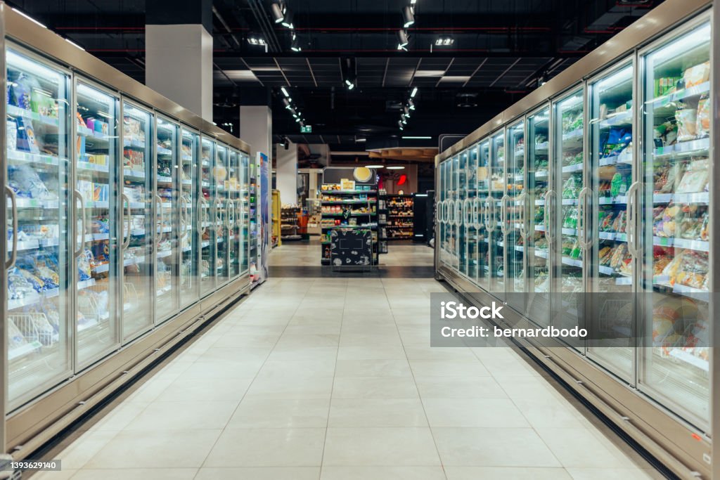 Empty supermarket aisle with refrigerators Empty supermarket aisle with freezers showcases with different products Supermarket Stock Photo