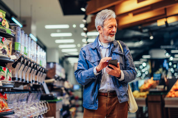 istock Smiling senior man using phone in grocery store 1393629895