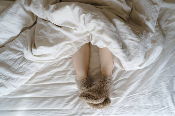 istock feet in wool socks under a blanket 1393630127
