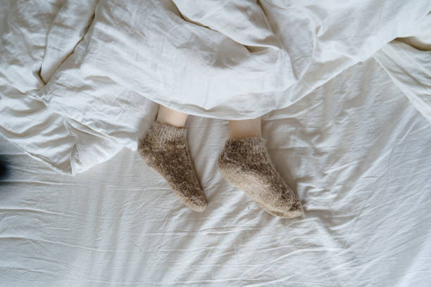 istock feet in wool socks under a blanket 1393630128