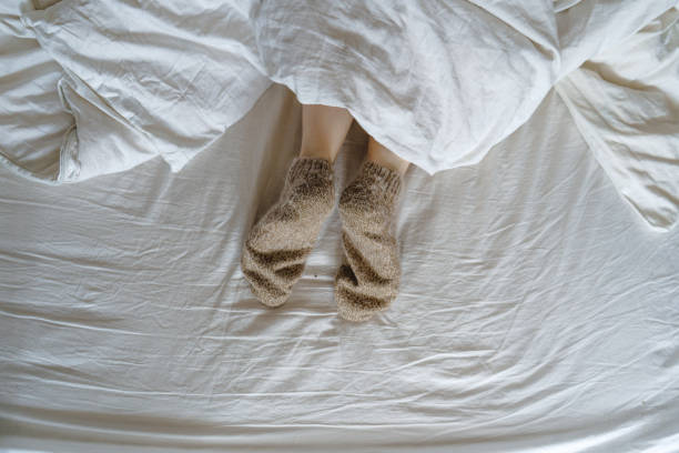 istock feet in wool socks under a blanket 1393630130