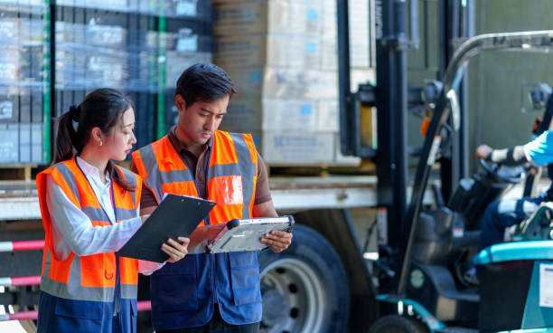 Warehouse workers discussing shipping schedule at Loading and unloading a lorry. Warehouse workers discussing shipping schedule at the background forklift lifting the goods into the truck. loading bay stock pictures, royalty-free photos & images