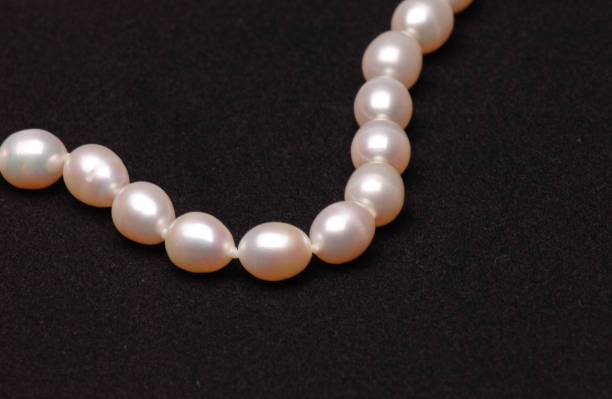 жемчужное ожерелье на матовом черном фоне. - black pearl pearl horizontal necklace стоковые фото и изображения