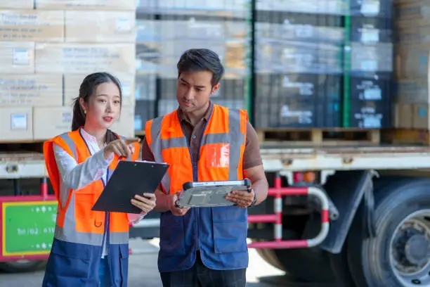 Photo of Warehouse workers discussing shipping schedule at Loading and unloading a lorry.