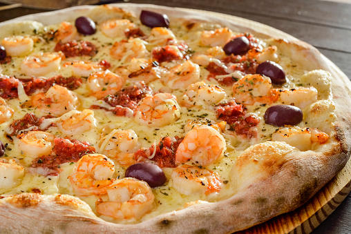 Pizza. Shrimp pizza with olives on wooden shovel close-up.